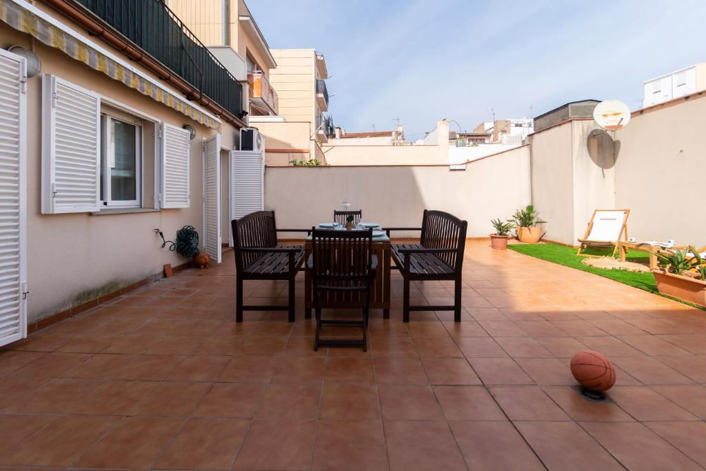 um pátio com uma mesa e cadeiras e uma bola de basquetebol em Apartamento con gran patio y excelente ubicación! em Mataró