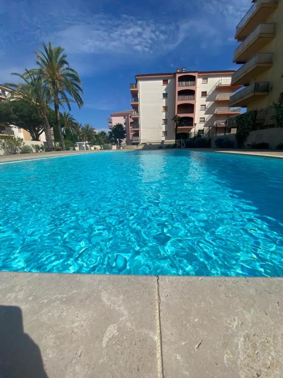 a large swimming pool in front of a building at La Palmeraie 2 chambres in Sainte-Maxime
