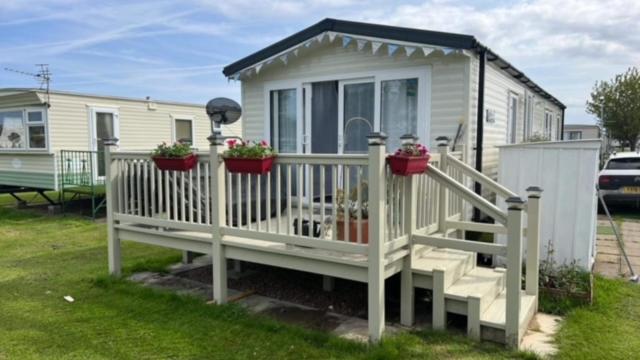 ein kleines Haus mit Topfpflanzen auf einer Veranda in der Unterkunft Skegness,North shore holiday park , new 8 berth caravan for rent in Skegness