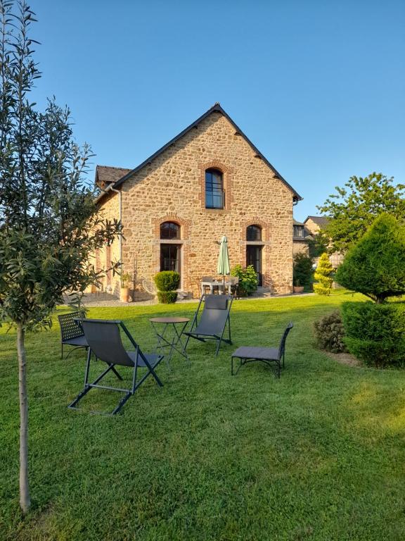 a group of chairs sitting in the grass in front of a house at La Sellerie in Romagné