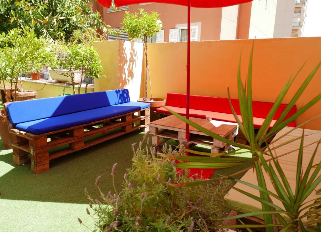 a patio with two benches and an umbrella at Palma Port Hostel - Albergue Juvenil in Palma de Mallorca