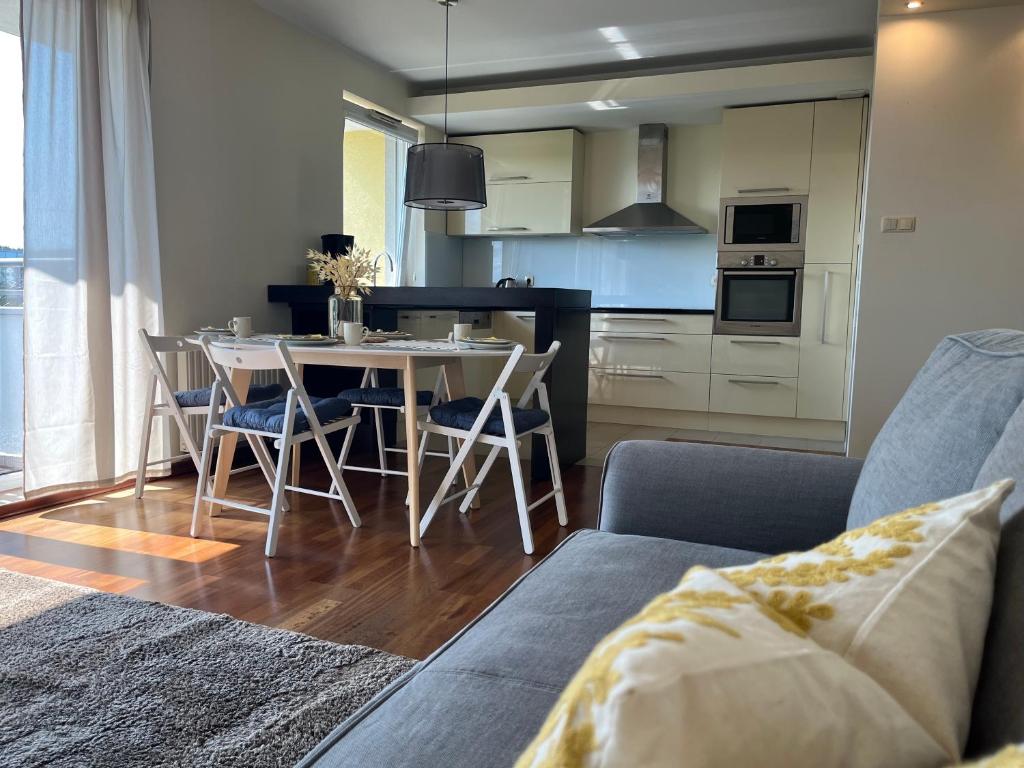 Prime Home SŁONECZNY في غدينيا: مطبخ وغرفة معيشة مع طاولة وكراسي
