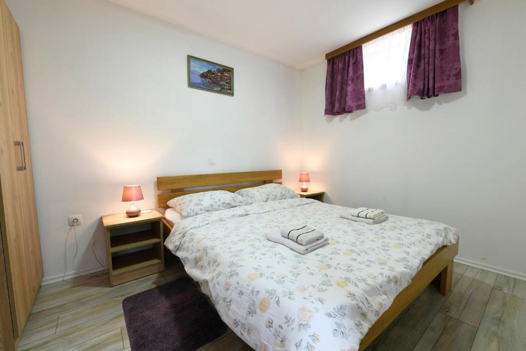 una camera con un letto con due comodini e due lampade di Apartman Jakov a Rakovica