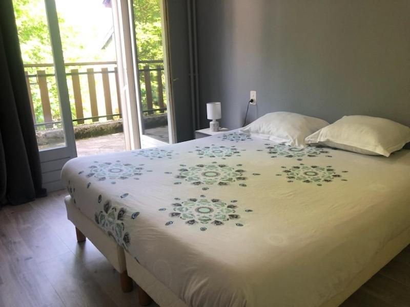 Una cama con una manta blanca con flores. en HOTEL BON ACCUEIL, en Oyonnax