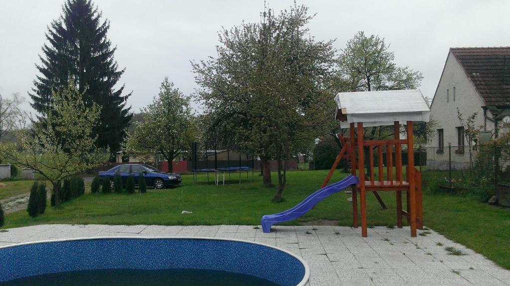 un parque infantil con tobogán junto a una piscina en Ubytování Macků, en Spolí