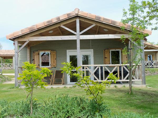 una pequeña casa con un gran porche con techo en Chalet nature proche lac et à 20 mn des plages en Vendée en La Chapelle-Hermier