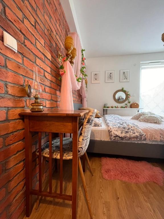 a bedroom with a brick wall and a desk and a bed at Apartament Harmony in Dębogórze