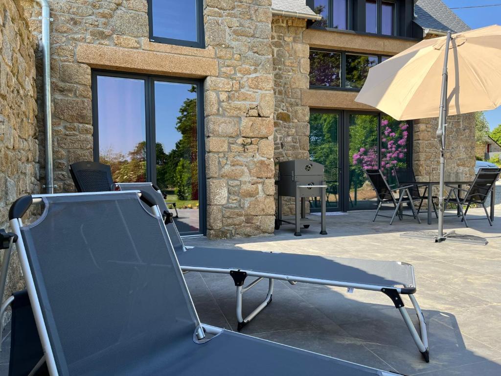 a bed in front of a building with an umbrella at Maison d'hôte avec sauna et jacuzzi à la campagne in Les Portes du Coglais