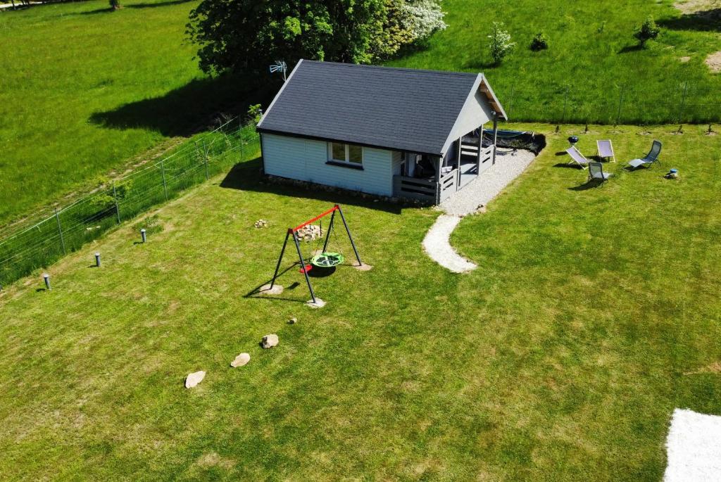 una pequeña casa en un campo con parque infantil en Domek Szarak, en Stary Gieraltów