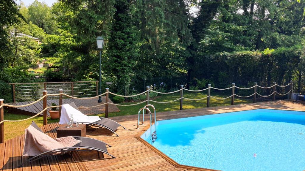 a pool on a wooden deck with chairs and a hammock at LA VALENTINE in Épinal