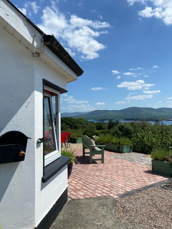 eine Terrasse mit einer Bank und Blick auf das Wasser in der Unterkunft Grenane Heights in Kenmare