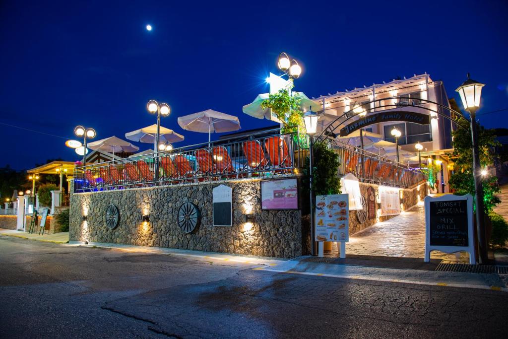 a building with chairs and umbrellas at night at Jasmine Hotel & Apartments in Agios Stefanos