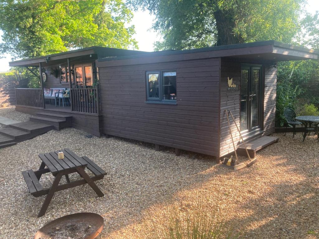 a small cabin with a picnic table and a picnic table at The Spinney lodge in Bubbenhall