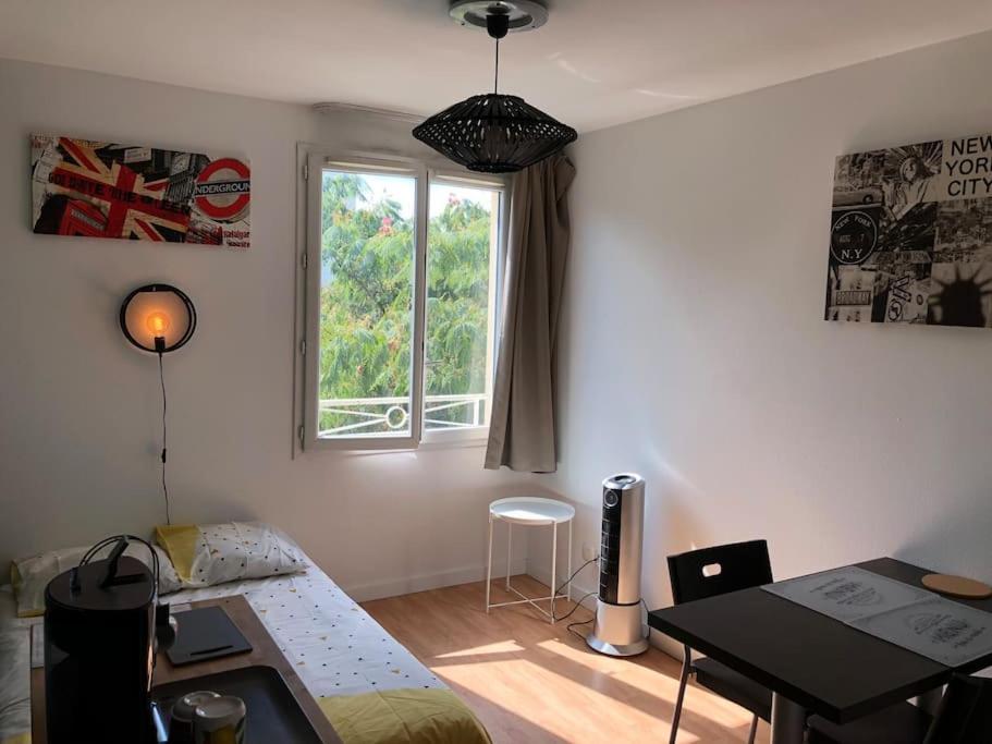 Zimmer mit einem Bett, einem Tisch und einem Fenster in der Unterkunft Charmant Studio Aix en Provence avec parking gratuit in Aix-en-Provence