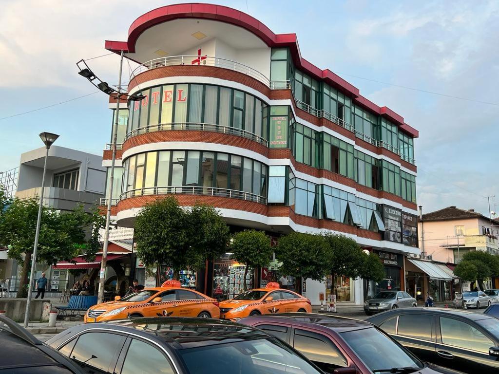 ein Gebäude mit Taxiautos, die davor geparkt sind in der Unterkunft Hotel W Bush Square in Fushë-Krujë