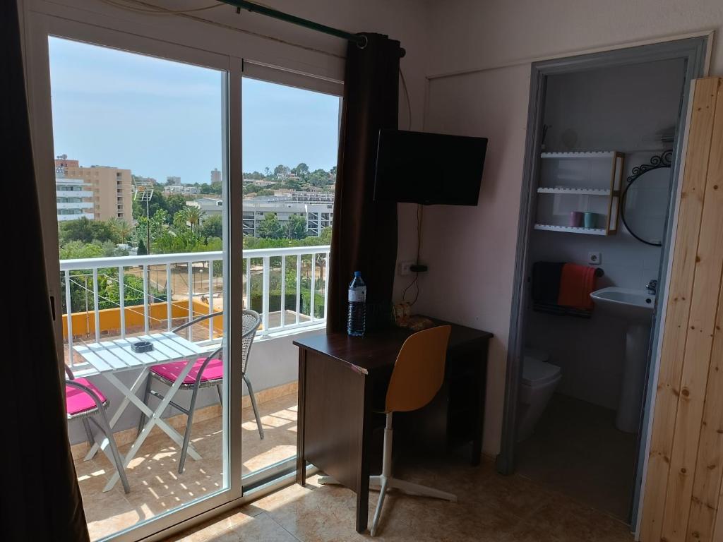 een kamer met een bureau en een balkon met uitzicht bij Hostal Bélgica in Palmanova