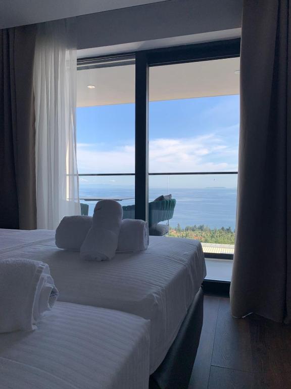 a bedroom with two beds and a large window at Black Diamond Hotel Dhermi in Dhërmi