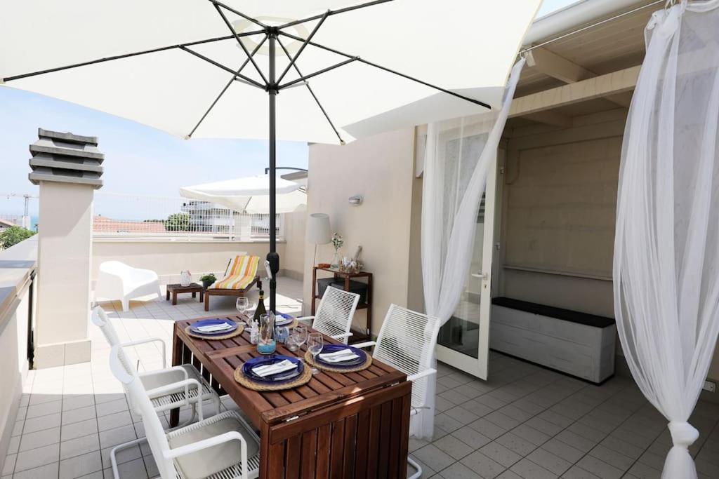 un patio con mesa de madera y sillas blancas en Casa Vivì en Porto SantʼElpidio