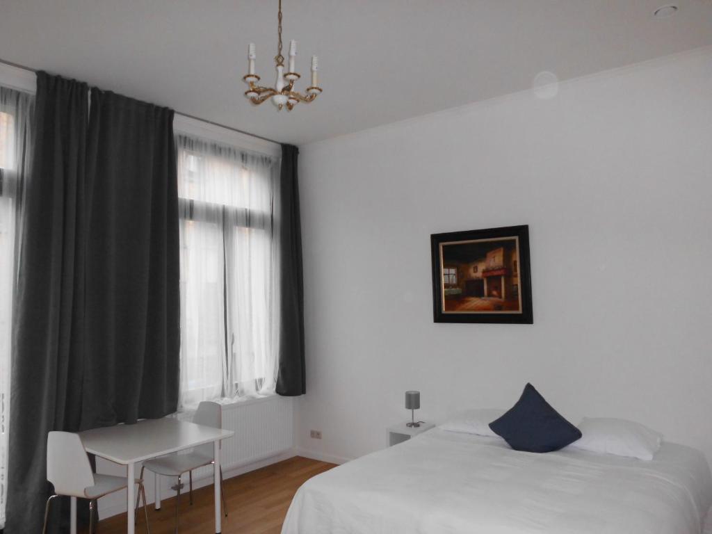 a bedroom with a bed and a desk and a window at Aparthotel Midi Residence in Brussels