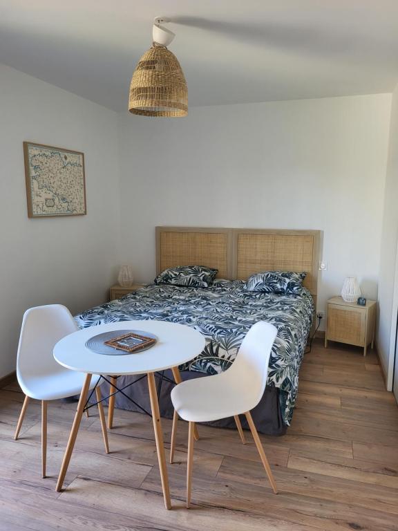een slaapkamer met een bed en een tafel en stoelen bij Le clos de la baie in Cancale