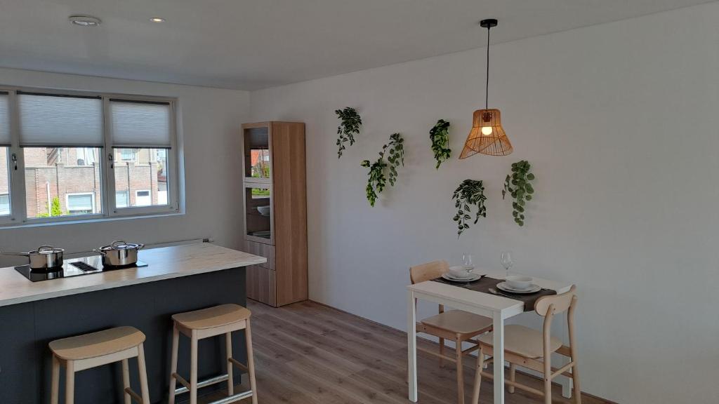 a kitchen with a counter and a table with stools at Appartement aan Zee in Noordwijk