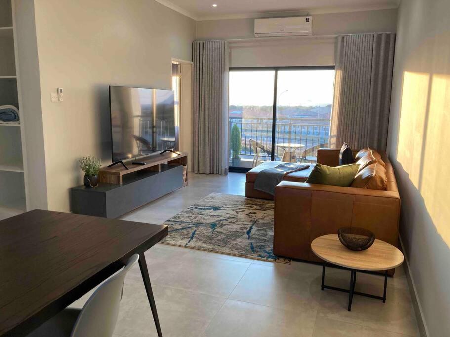 a living room with a couch and a bed at Urban Awe Apartment: Sarona City in Gaborone