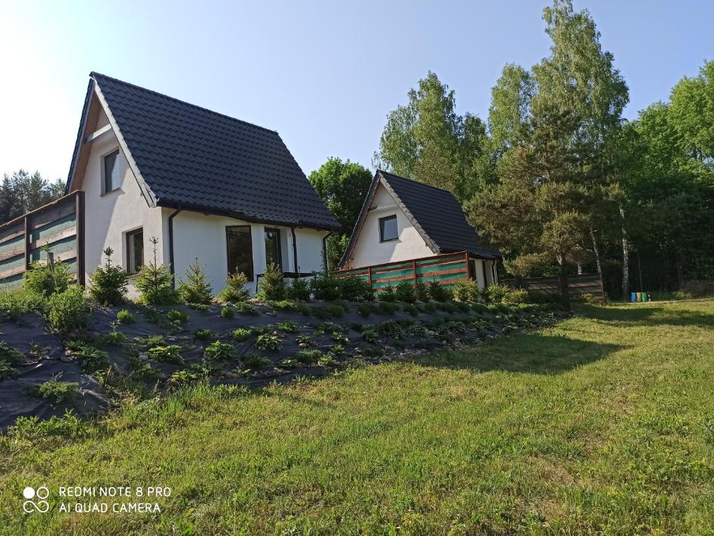 uma casa com um telhado preto num campo verde em Urokliwy domek na mazurach em Pilec
