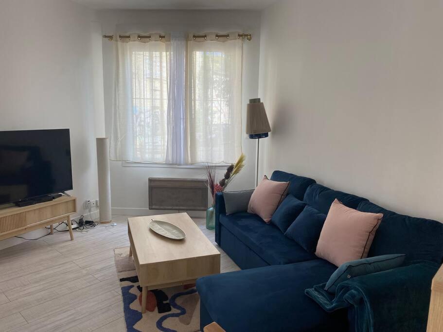 uma sala de estar com um sofá azul e uma mesa em Appartement cosy à Bordeaux em Bordeaux