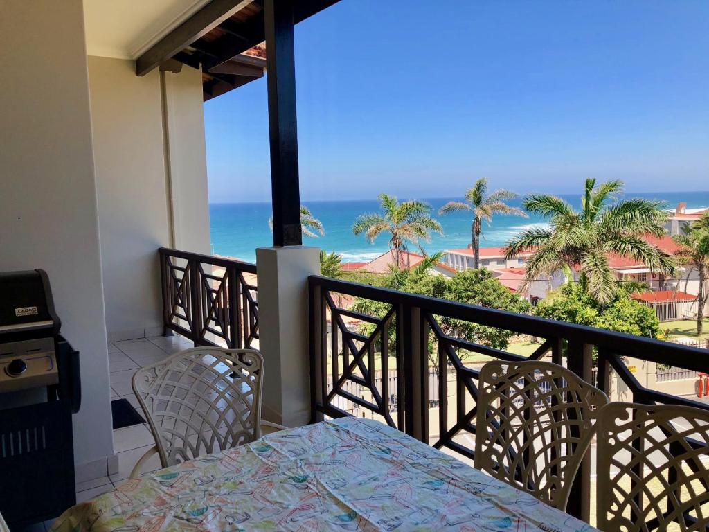 een balkon met een tafel en stoelen en de oceaan bij Topanga 70, Uvongo in Margate