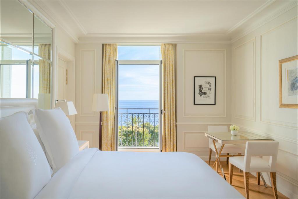 a bedroom with a bed and a table and a window at Grand-Hôtel du Cap-Ferrat, A Four Seasons Hotel in Saint-Jean-Cap-Ferrat
