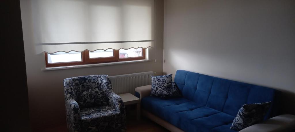uma sala de estar com um sofá azul e duas cadeiras em Lux daire em Yeniköy