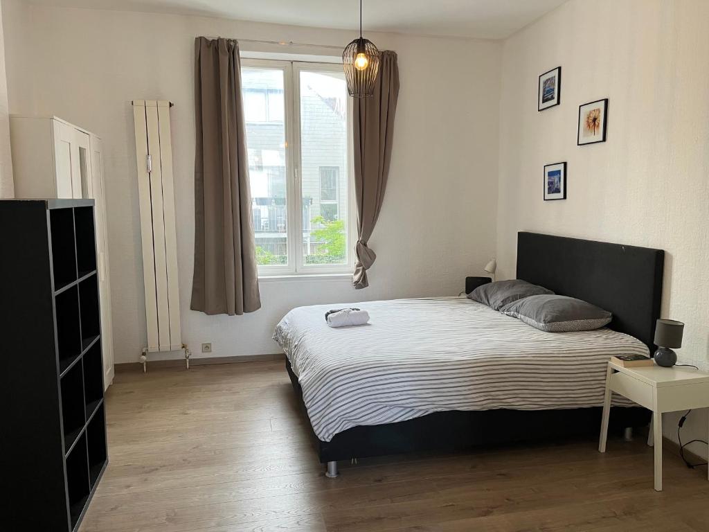 een slaapkamer met een bed en een raam bij Uccle Chic Flat in Brussel