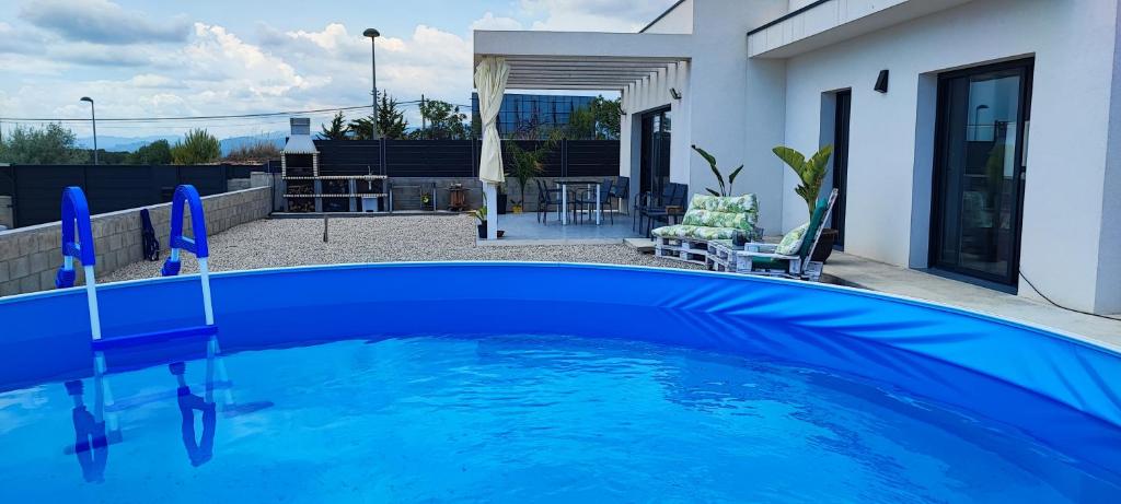 una gran piscina azul frente a una casa en Chalet con piscina, terraza y barbacoa en Pallaresos