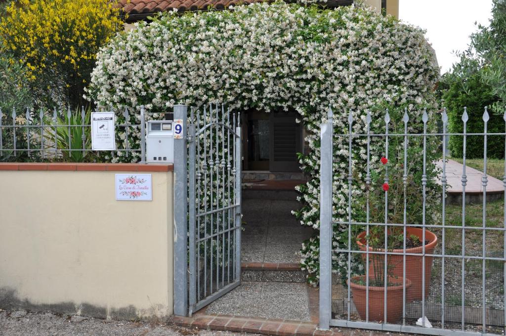 una puerta abierta con flores blancas detrás de una valla en La Casa di Fiorella, en Cerreto Guidi