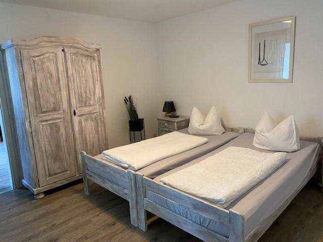 a bedroom with two beds and a wooden cabinet at Pension Sandfeld in Teterow