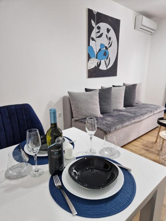 a table with a plate and wine glasses on it at Apartman Astra in Sremska Mitrovica