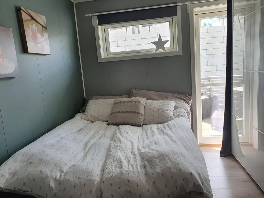 a bed with a white comforter in a bedroom at Nydelig leilighet- Solrik/2 balkonger in Seim
