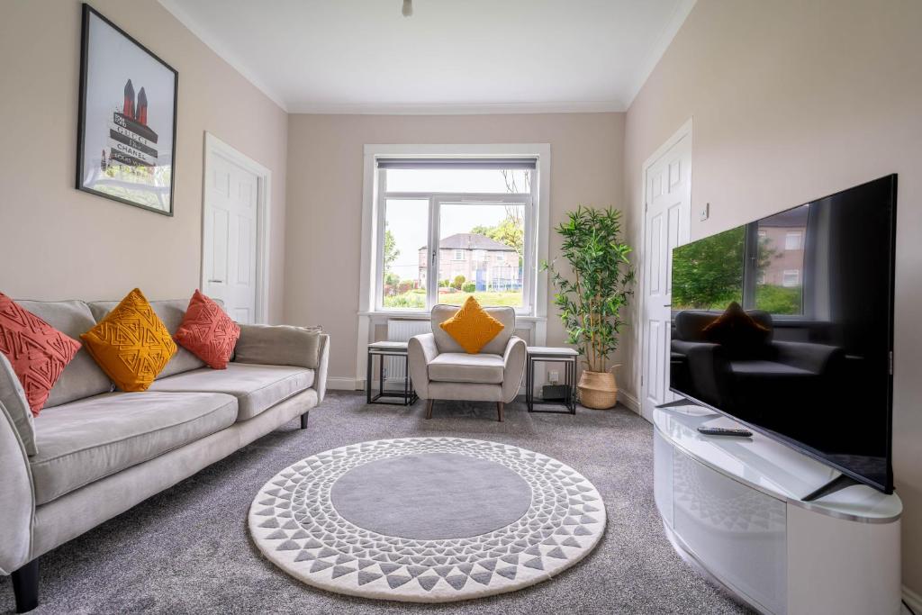a living room with a couch and a tv at 4 Bedrooms Homely House - Sleeps 6 Comfortably with 6 Double Beds,Glasgow, Free Street Parking, Business Travellers, Contractors, & Holiday-Goers, Near All Major Transport Links in Glasgow & City Centre in Glasgow