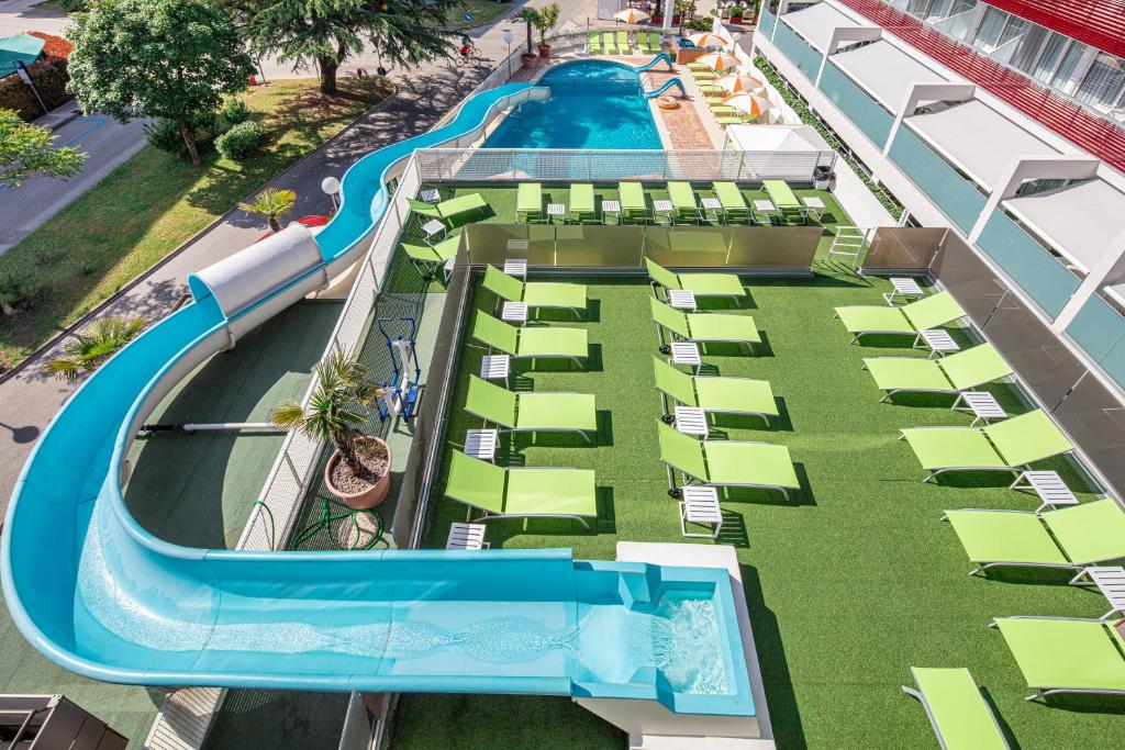 een luchtzicht op een zwembad van het resort met stoelen en een waterglijbaan bij Hotel Alexander in Bibione