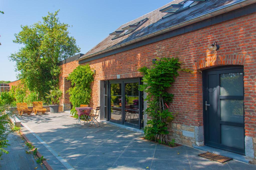 a brick building with a door and a patio at Gîtes de la Chapelle in Assesse