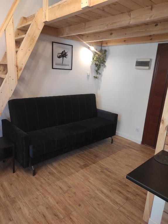 een zwarte bank in een woonkamer met een houten vloer bij Apartament Katedralna Centrum in Częstochowa