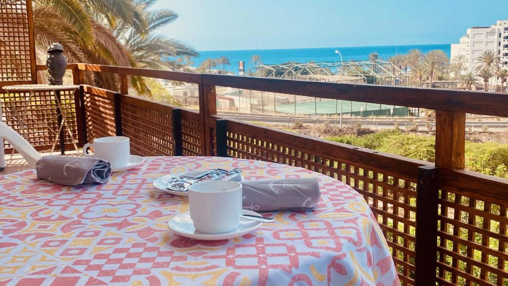 een tafel op een balkon met uitzicht op het strand bij Click&Guest - Red Rock Apartment in Maspalomas in Playa del Inglés