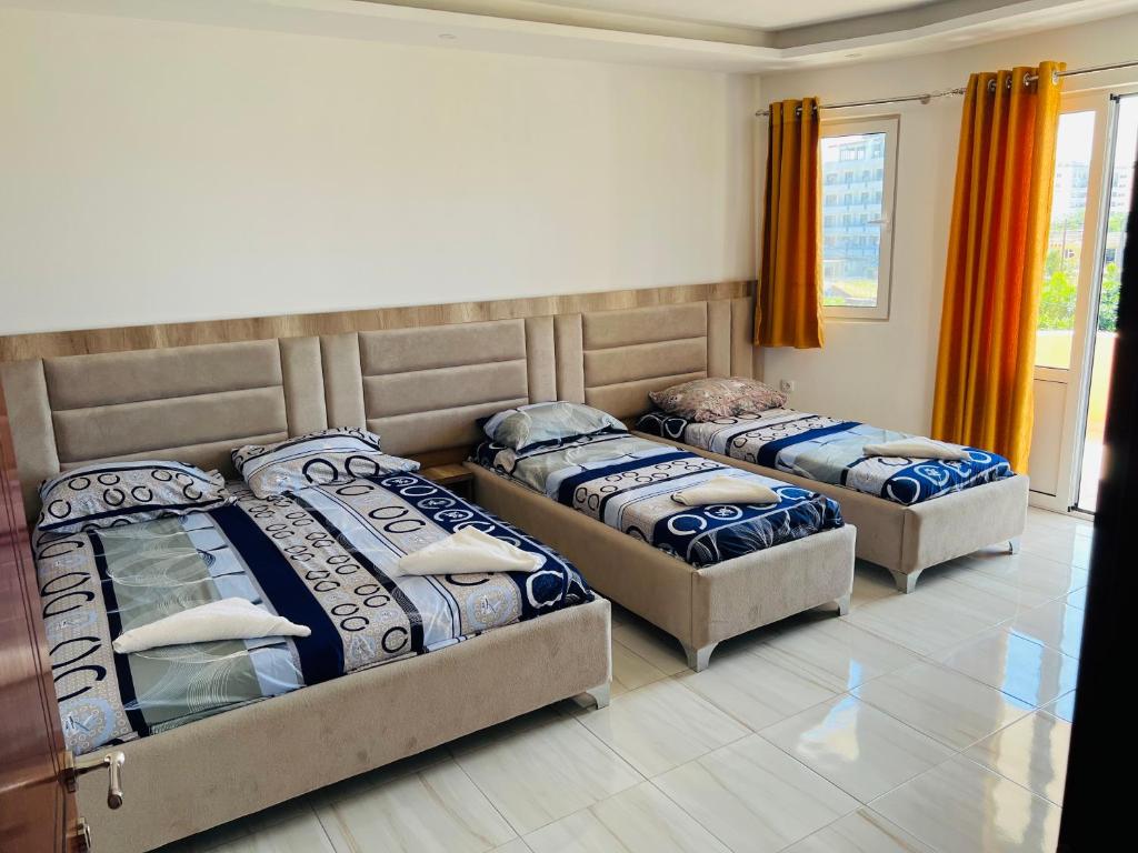 three beds in a bedroom with orange curtains at Apartments Betti in Ulcinj