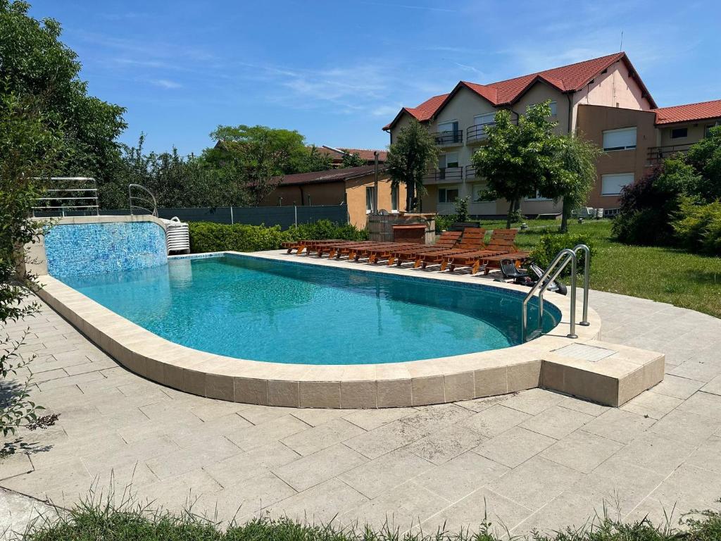 a swimming pool with benches in a yard at Venus Resort in Dumbrăviţa