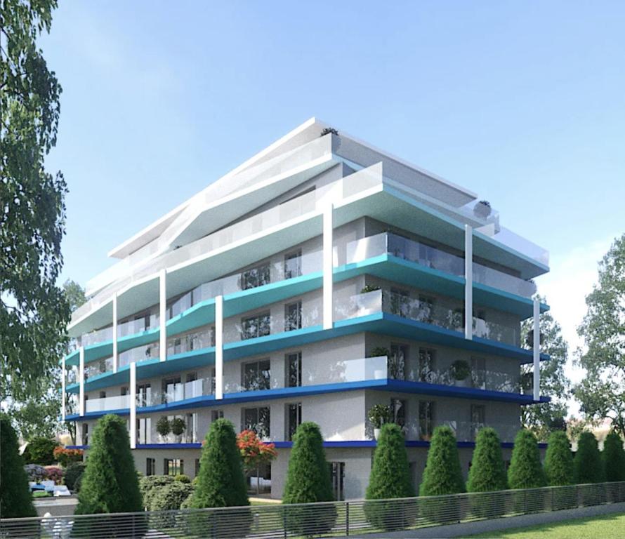 apartamentowiec z niebieskimi balkonami i drzewami w obiekcie Mistral Helka Apartman w Balatonföldvárze