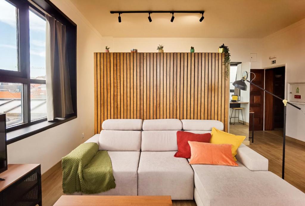 uma sala de estar com um sofá branco com almofadas coloridas em Ninho 424 no Porto