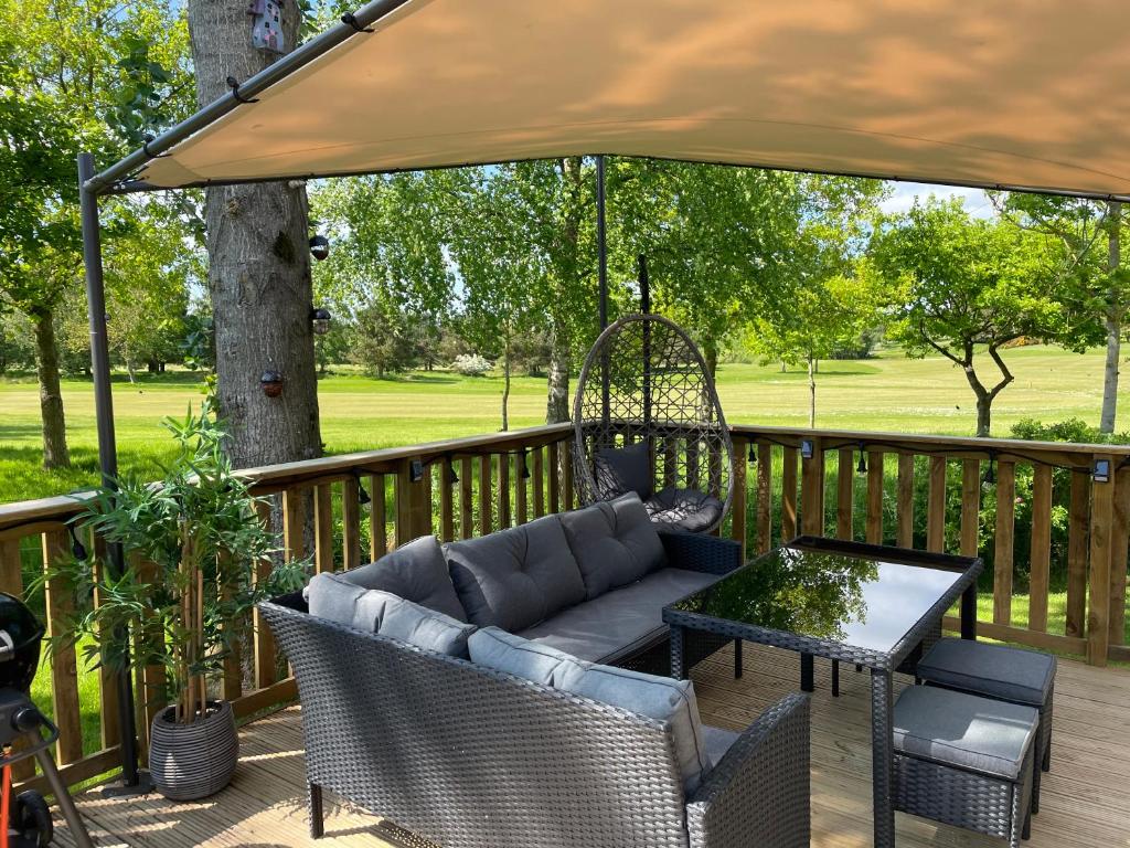 a patio with a couch and a table on a deck at Teviotdale Lodge at Lilliardsedge Holiday Park in Jedburgh