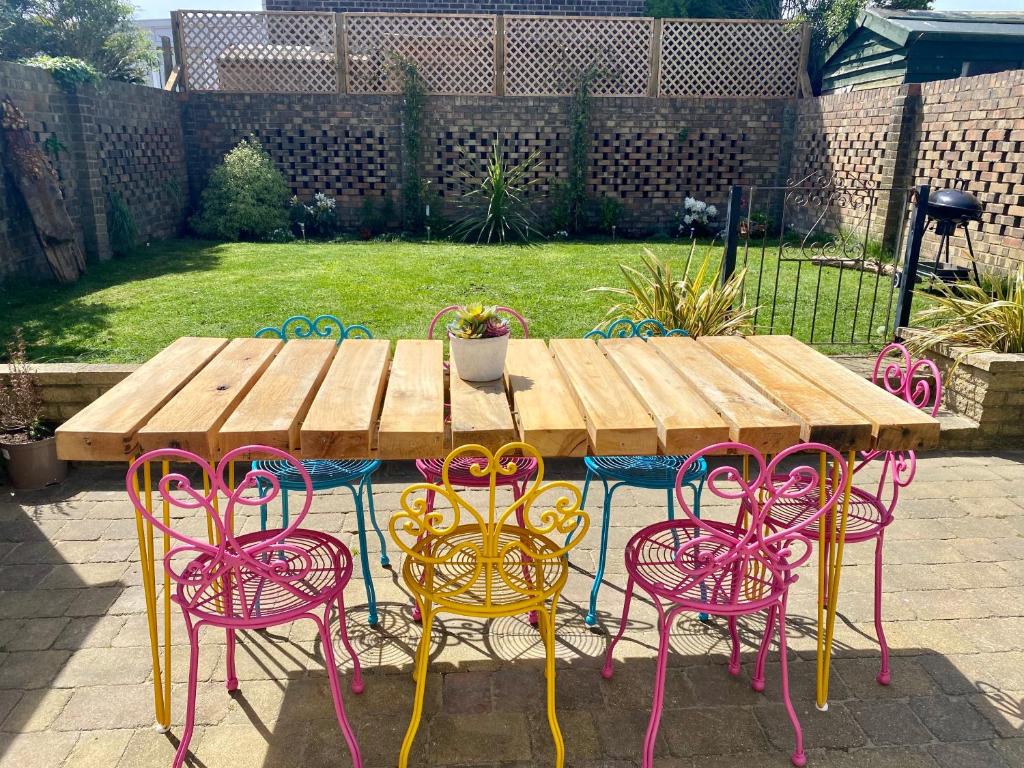 a wooden table with pink and yellow chairs around it at 1min walk to Beach- Happy Waves- Family Home in Camber