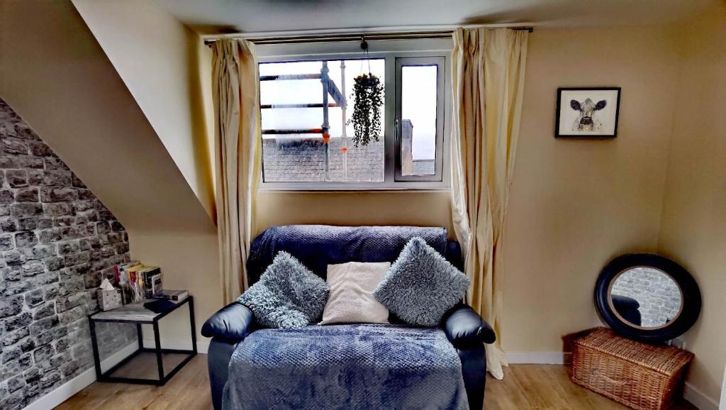 ein blaues Sofa in einem Zimmer mit Fenster in der Unterkunft Cozy Loft In The Heart Of Kirkwall in Orkney