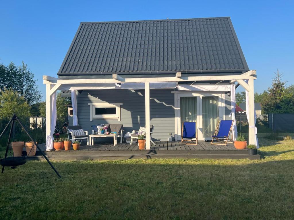 uma casa com um gazebo com duas cadeiras azuis em Blisko morza em Słajszewo